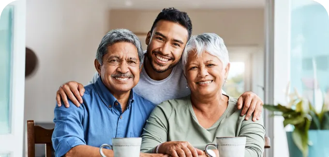 Elderly couple and son smiling while at the table