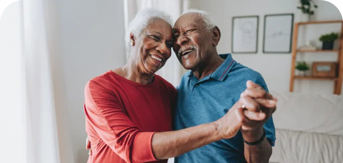 Elderly couple smiling and holding each other while dancing