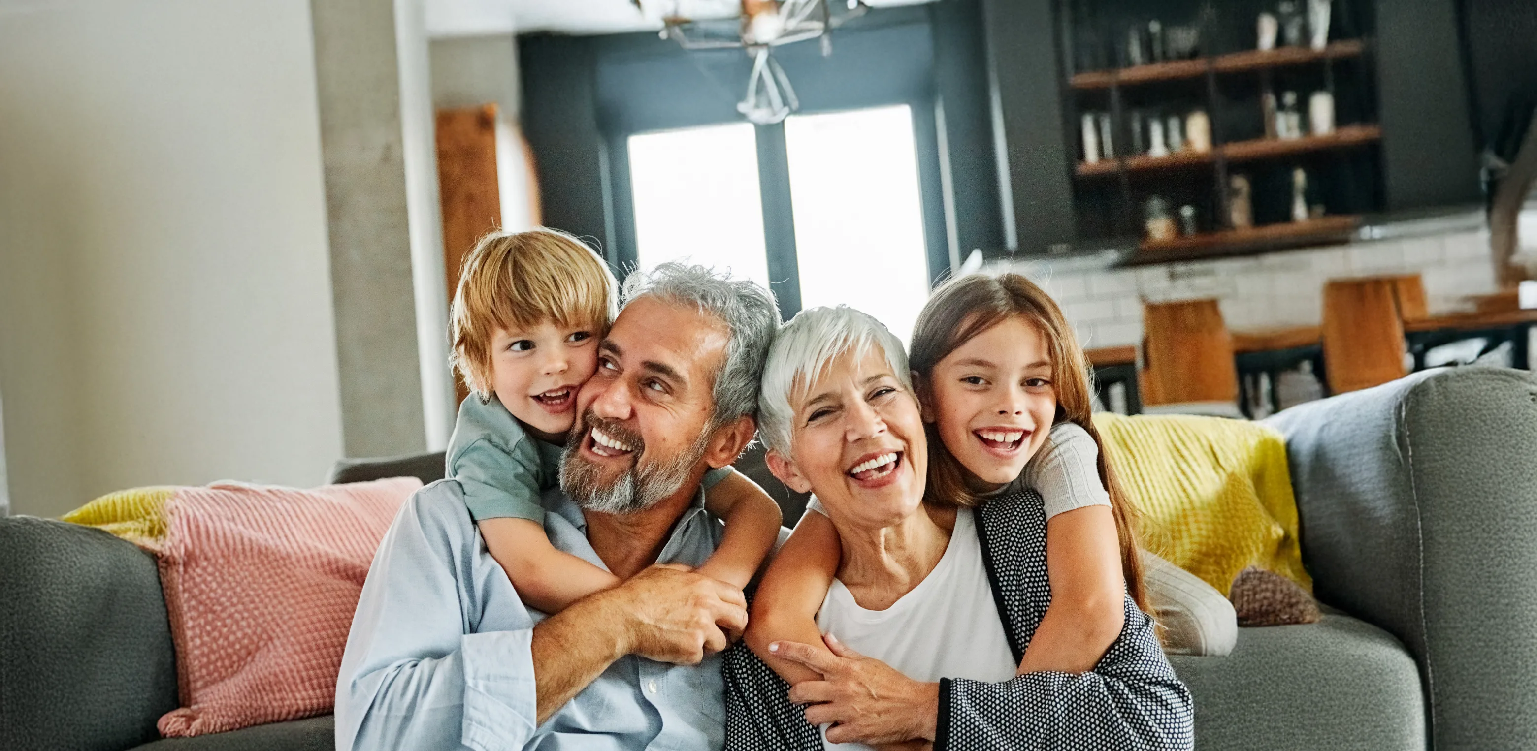 Older couple smiling while holding their grand kids on couch