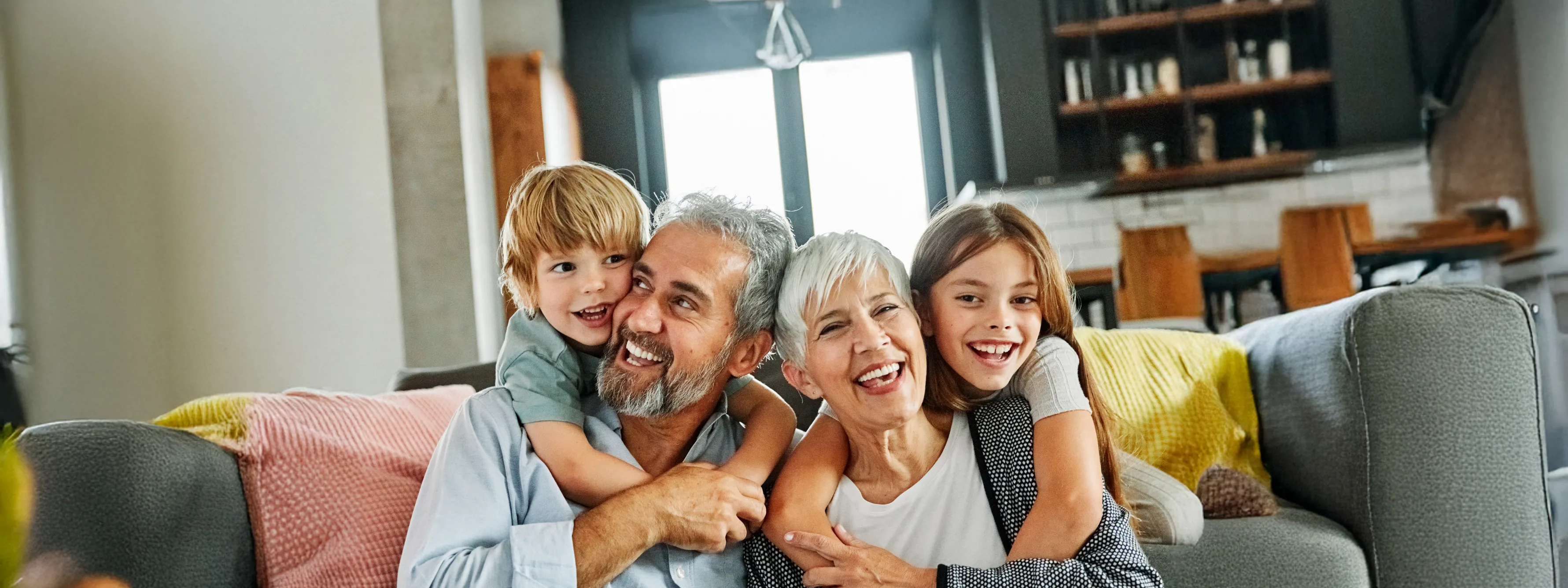 Older couple smiling while holding their grand kids on couch