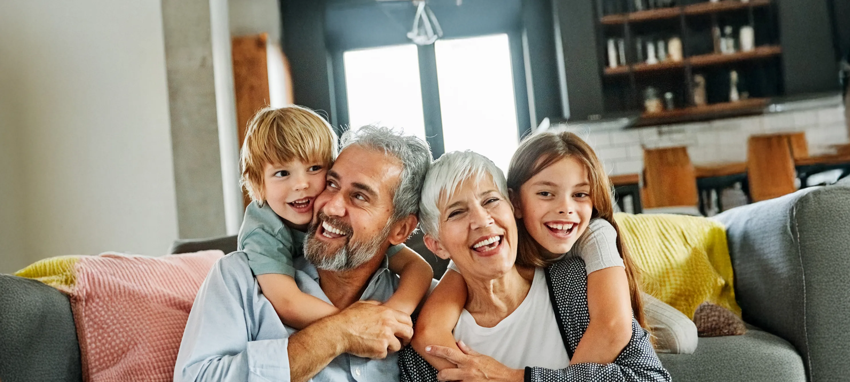 Older couple smiling while holding their grand kids on couch