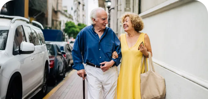 Elderly couple walking down the street holding arms