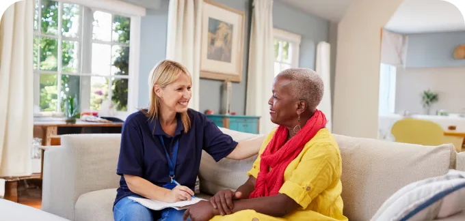 Female Social worker supporting female patient while sitting on a couch
