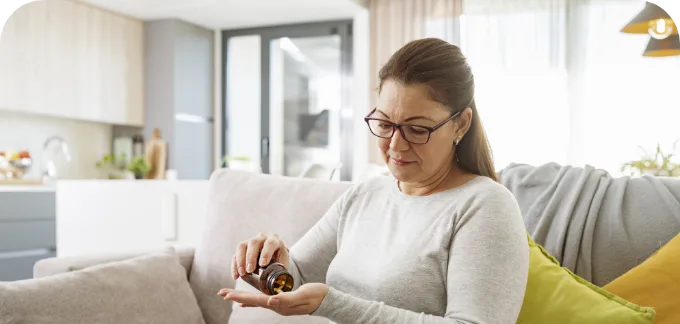 Woman with glasses taking prescriptions out of a pill bottle