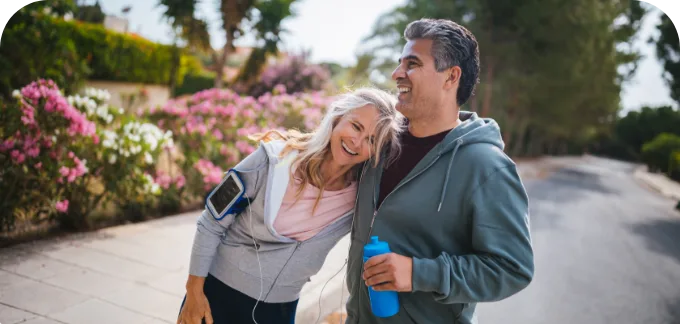Couple outside smiling at each other and holding each other while out for a walk